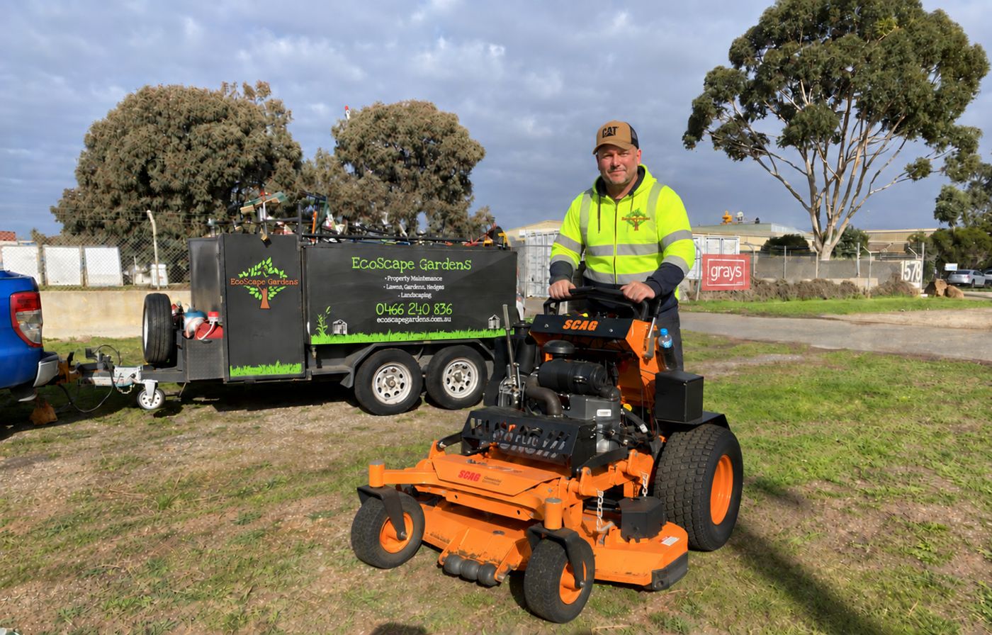 EcoScape Gardens commercial stand-on mower and branded trailer on site